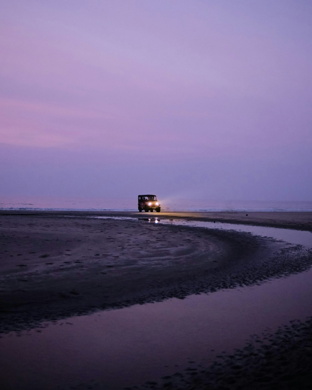 a truck driving down a road next to a body of water