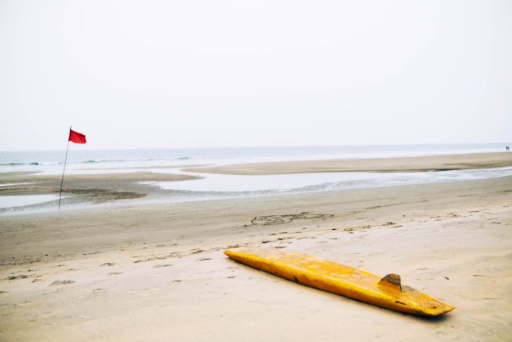a yellow surfboard laying on a sandy beach