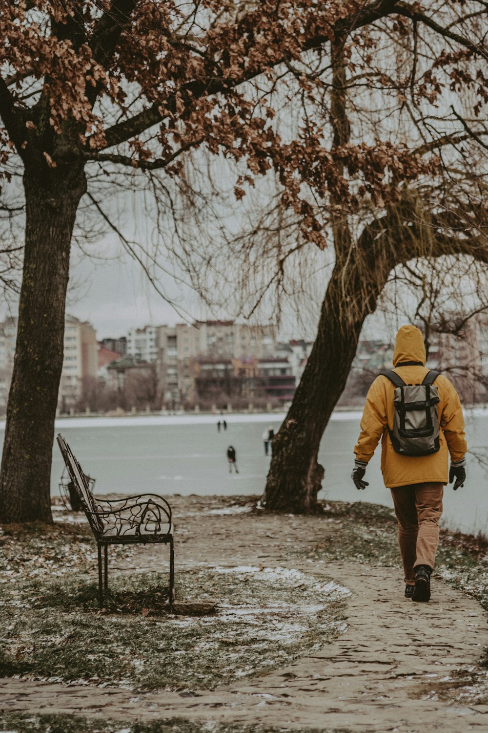 a person in a yellow jacket is walking near a bench