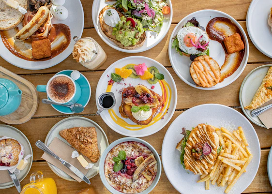 A vibrant brunch plate with tropical fruits and fusion dishes artfully arranged on a rustic wooden table.