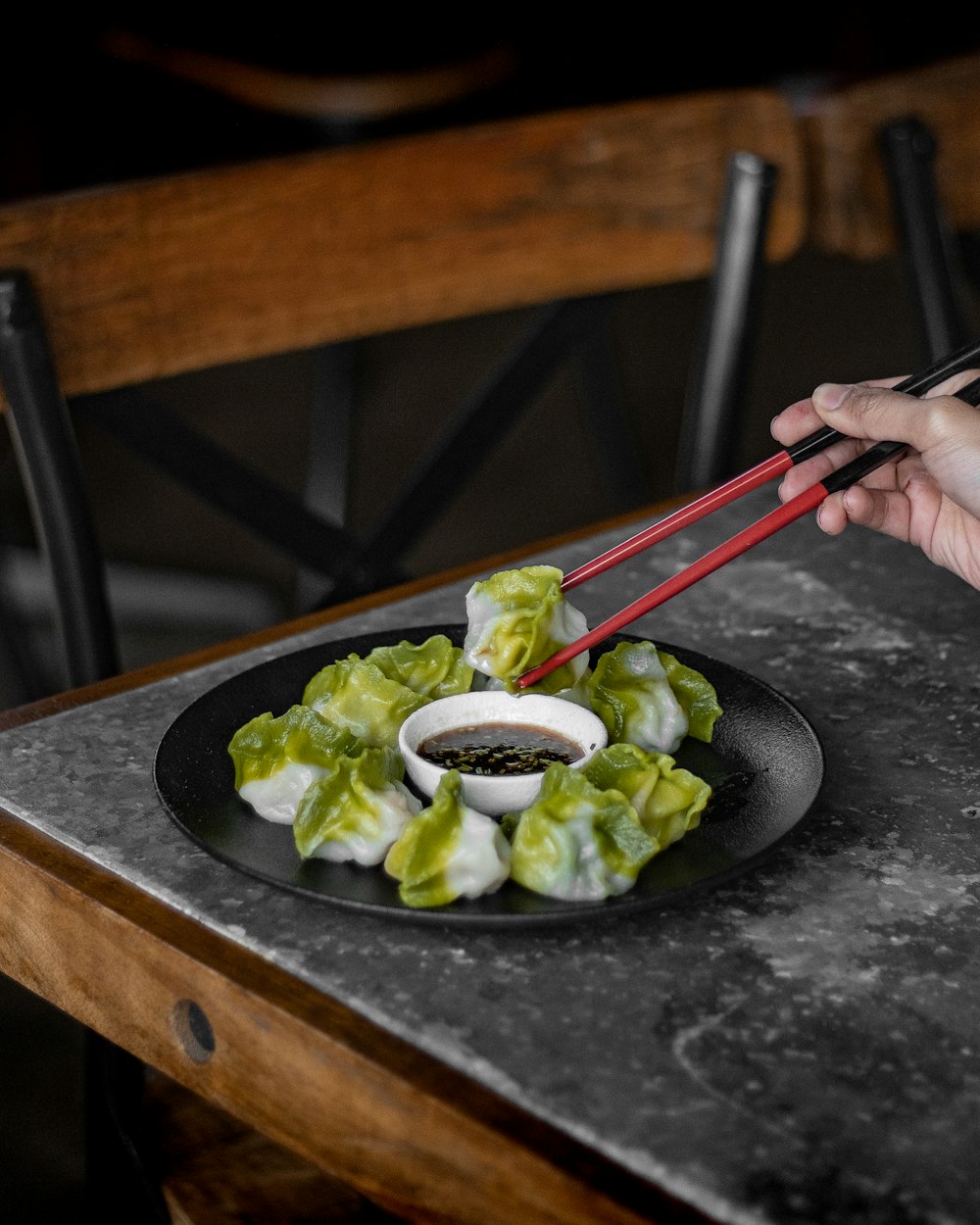 a person holding chopsticks over a plate of food