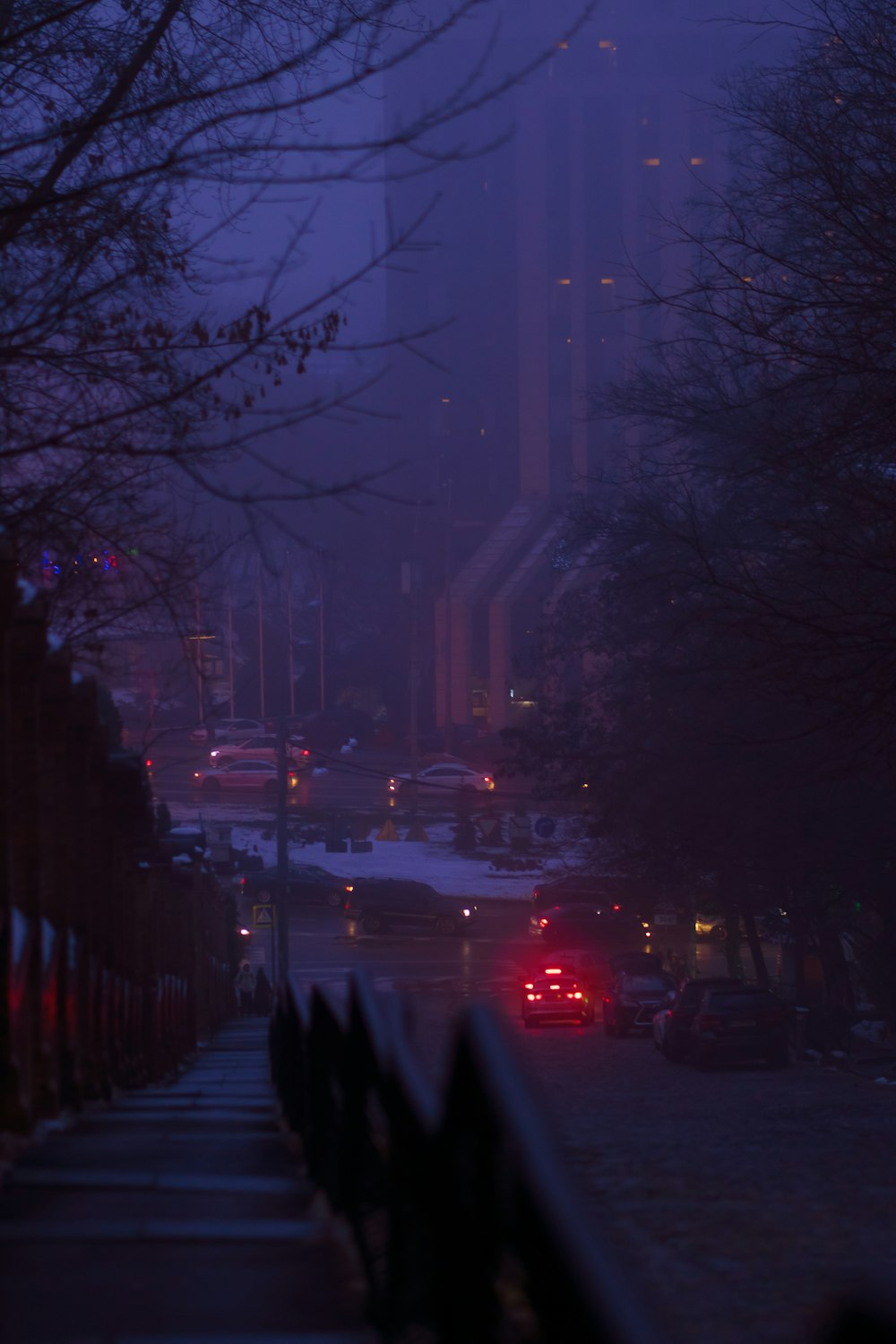 a city street at night with cars parked on the side of the road