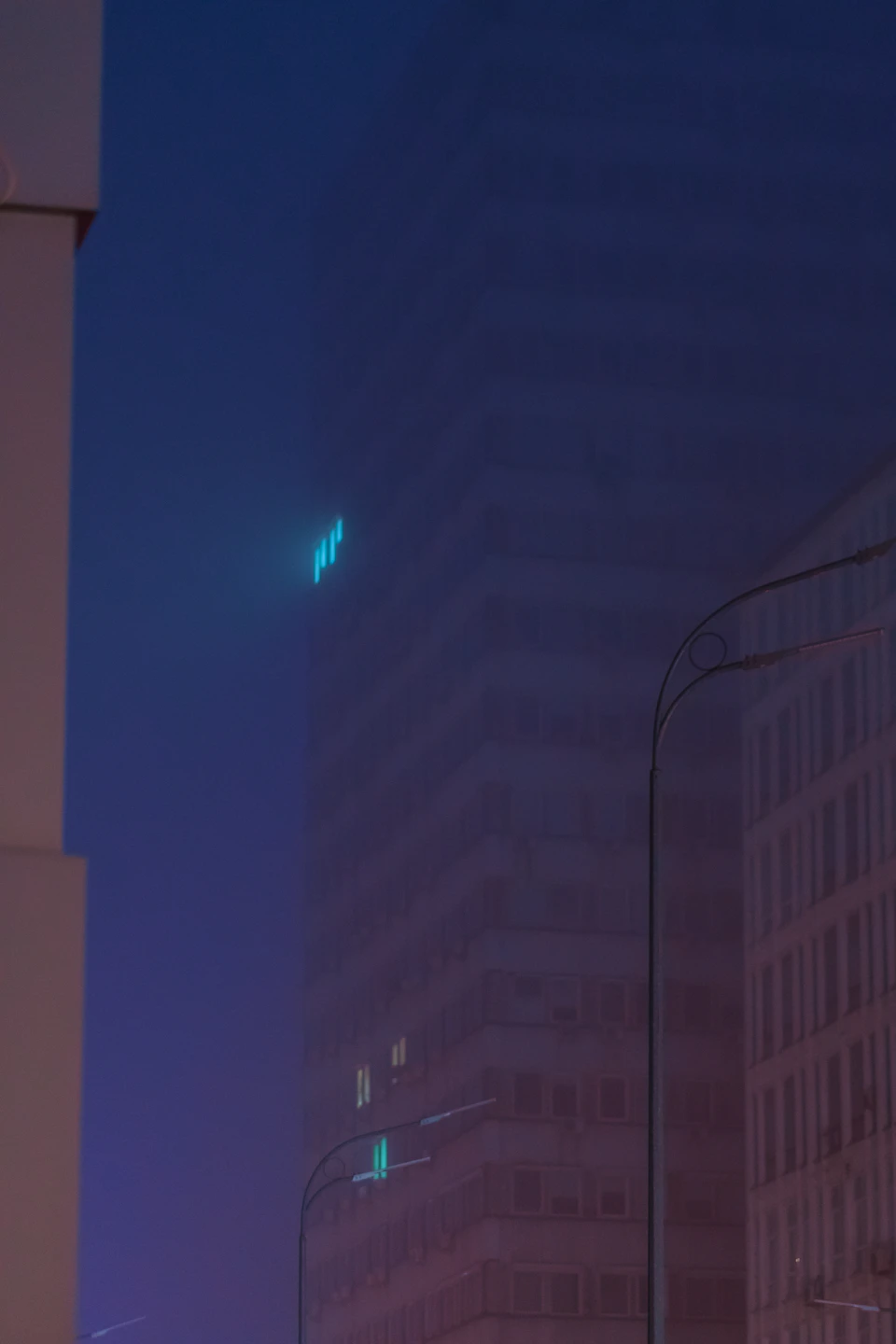 Tall white building with two windows and blue neon sign reading BAR at night