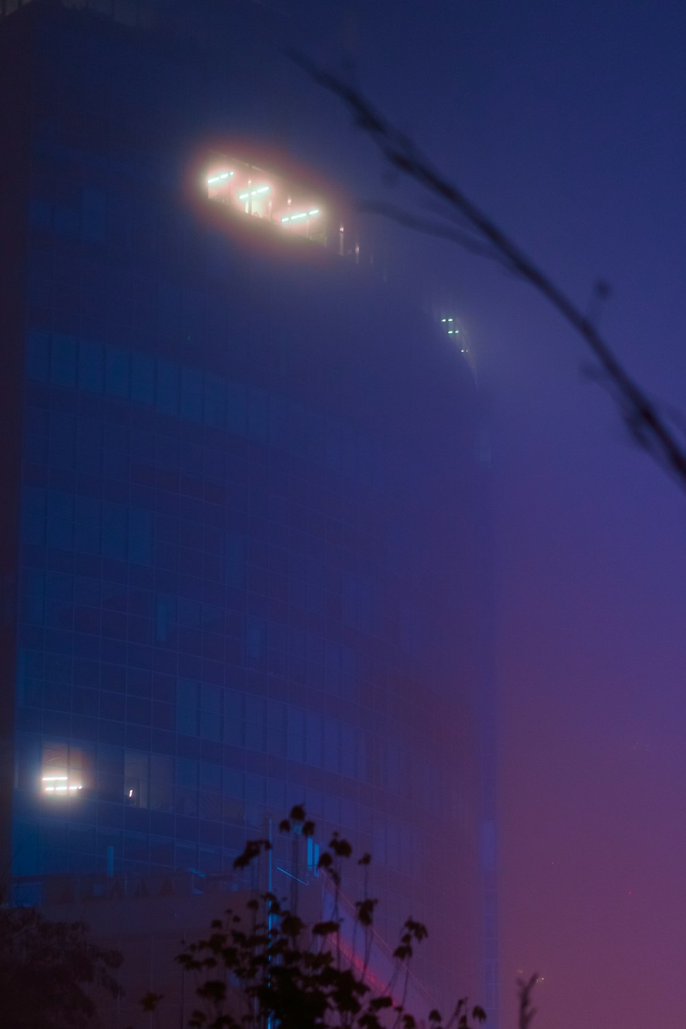 a foggy night in a city with a tall building
