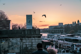 Scenic view of Malecón del Río with people walking and boats on the river at sunset