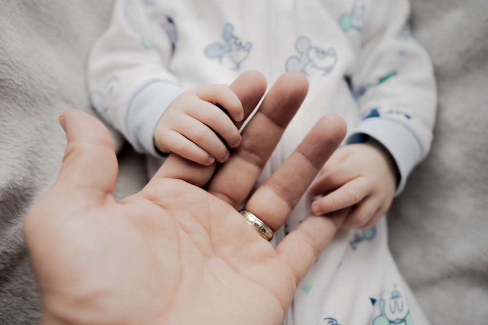 a person holding a baby's hand with a ring on it