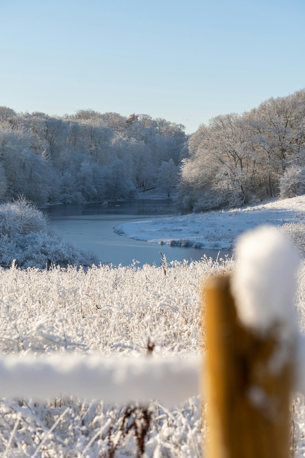 a snow covered field with a lake in the background
