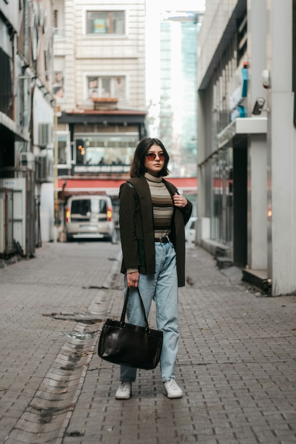 a woman standing on a street holding a bag