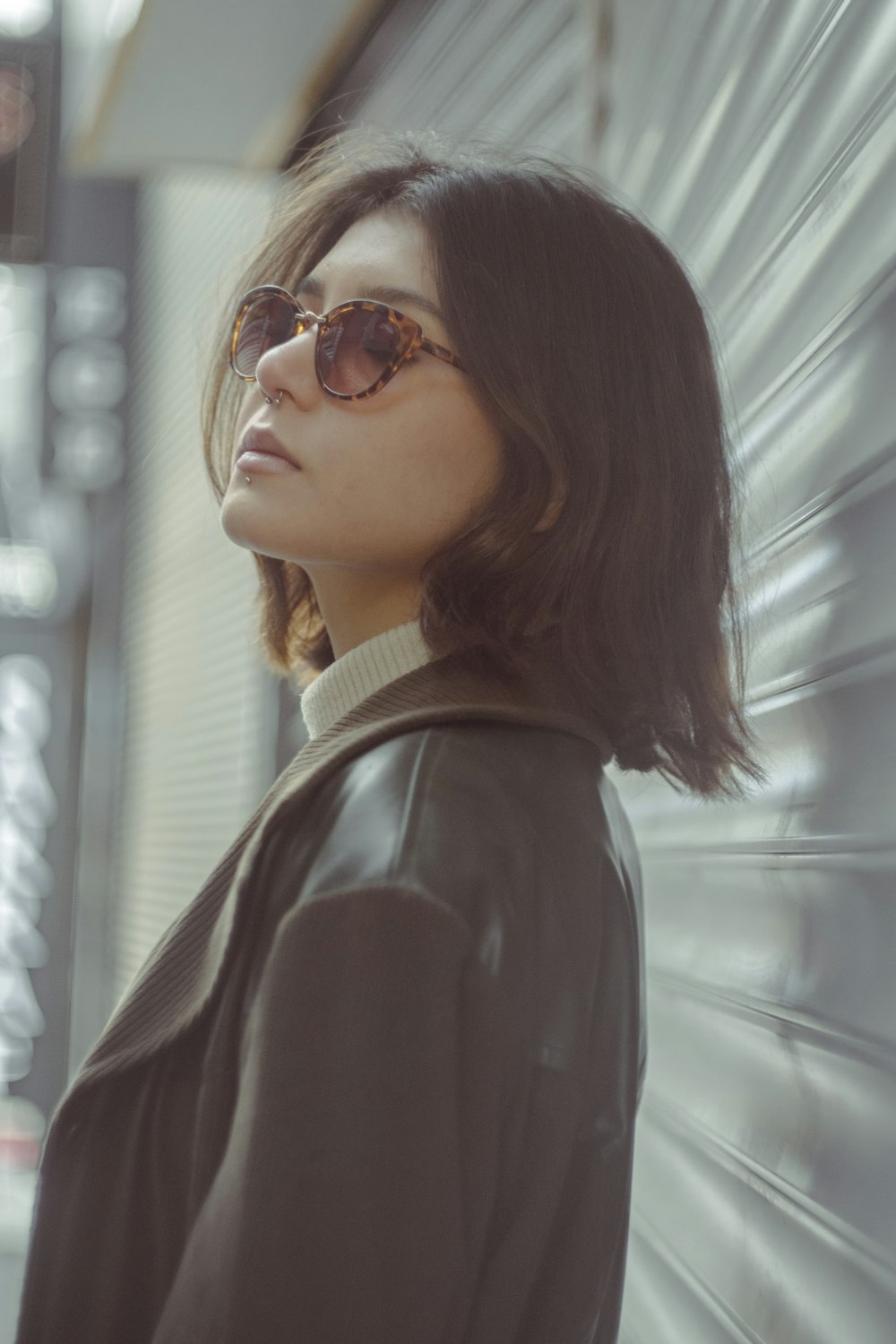 a woman wearing sunglasses standing in front of a wall