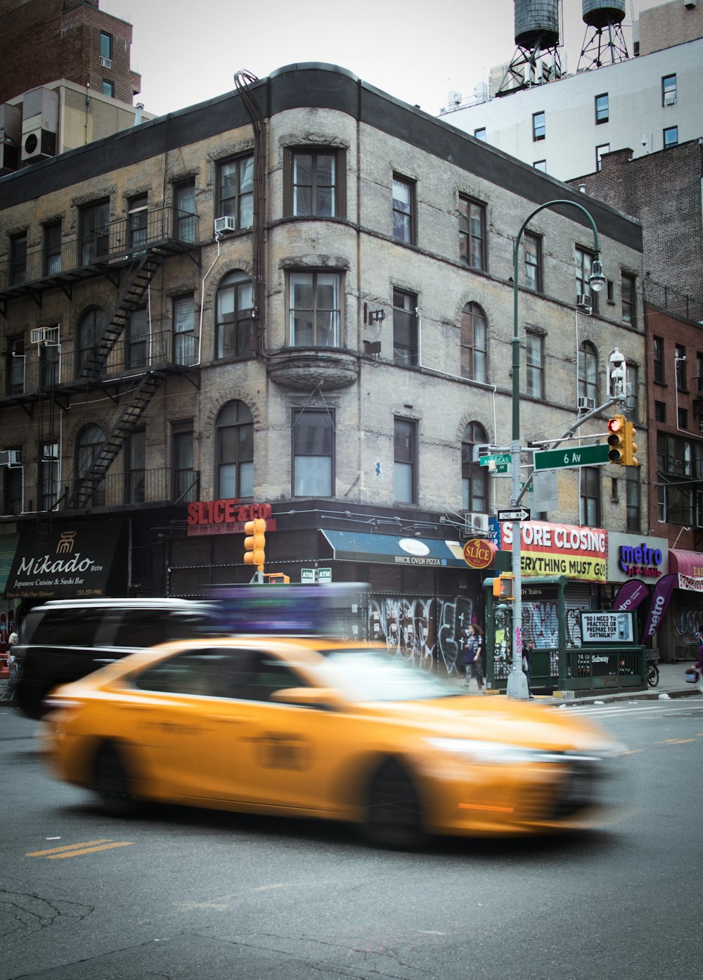 a yellow taxi driving down a street next to tall buildings