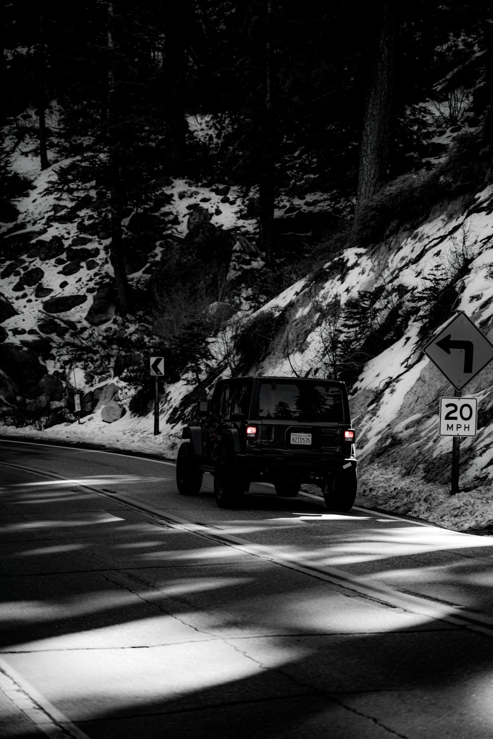 a jeep driving down a road next to a forest