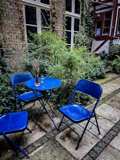 A backyard garden with blue flowers and a small seating area.