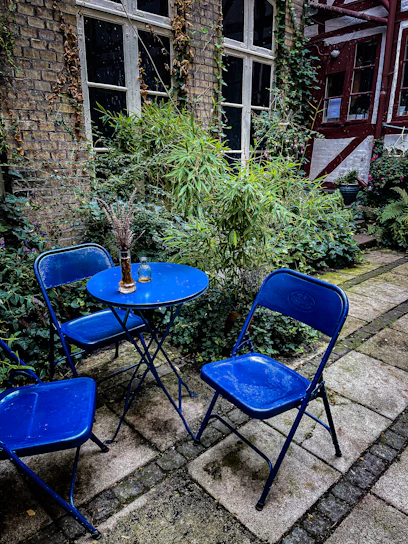 A compact apartment patio setup with a small table, two swivel metal outdoor club chairs, and leafy plants creating a snug vibe.