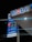 A gas station sign is illuminated at night, featuring the Mobil logo prominently. Various services are advertised, including a car wash and Mobil Mart. The prices of different types of fuel are displayed digitally, with labels for Super Plus and another grade. The backdrop of the image is predominantly dark, highlighting the brightly lit sign.
