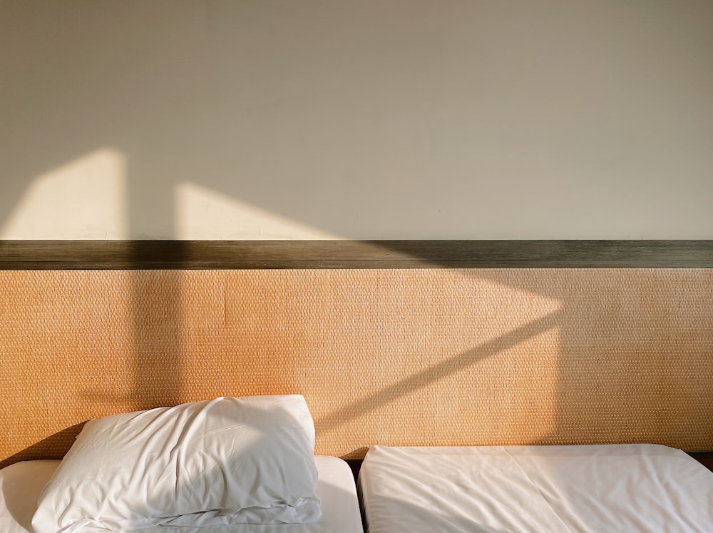 a bed with two white pillows and a wooden headboard