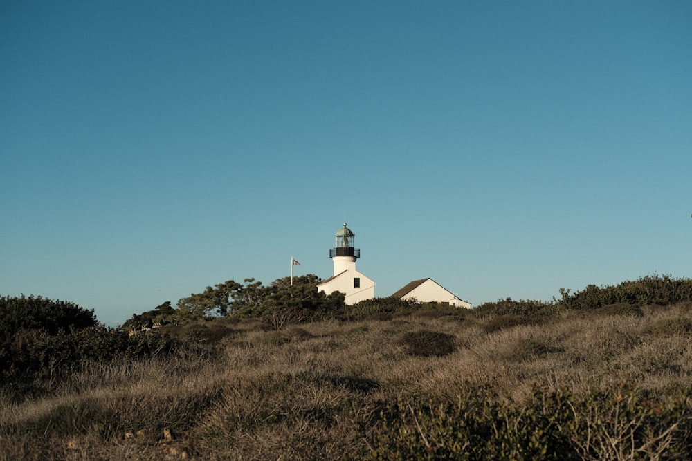 a lighthouse on top of a hill with a blue sky in the background