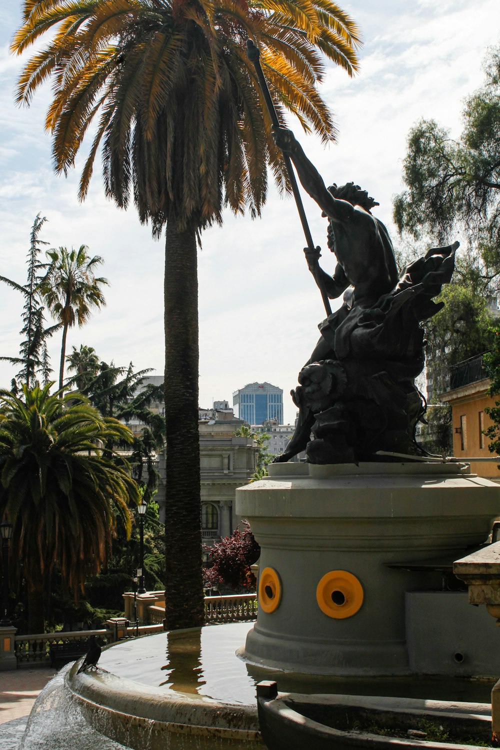 a statue of a man riding a horse next to a palm tree