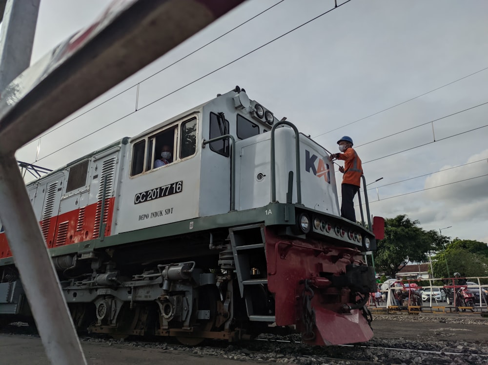 a man standing on top of a train on a train track