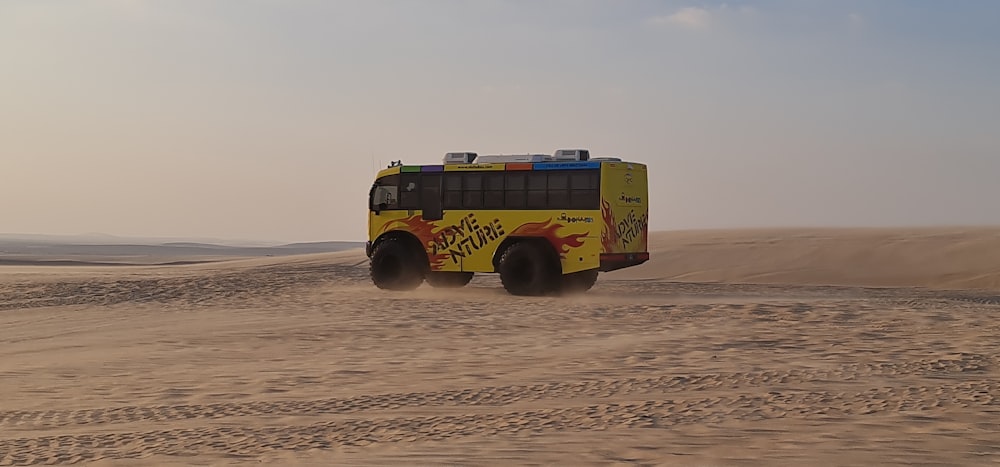 a yellow bus driving through a sandy desert