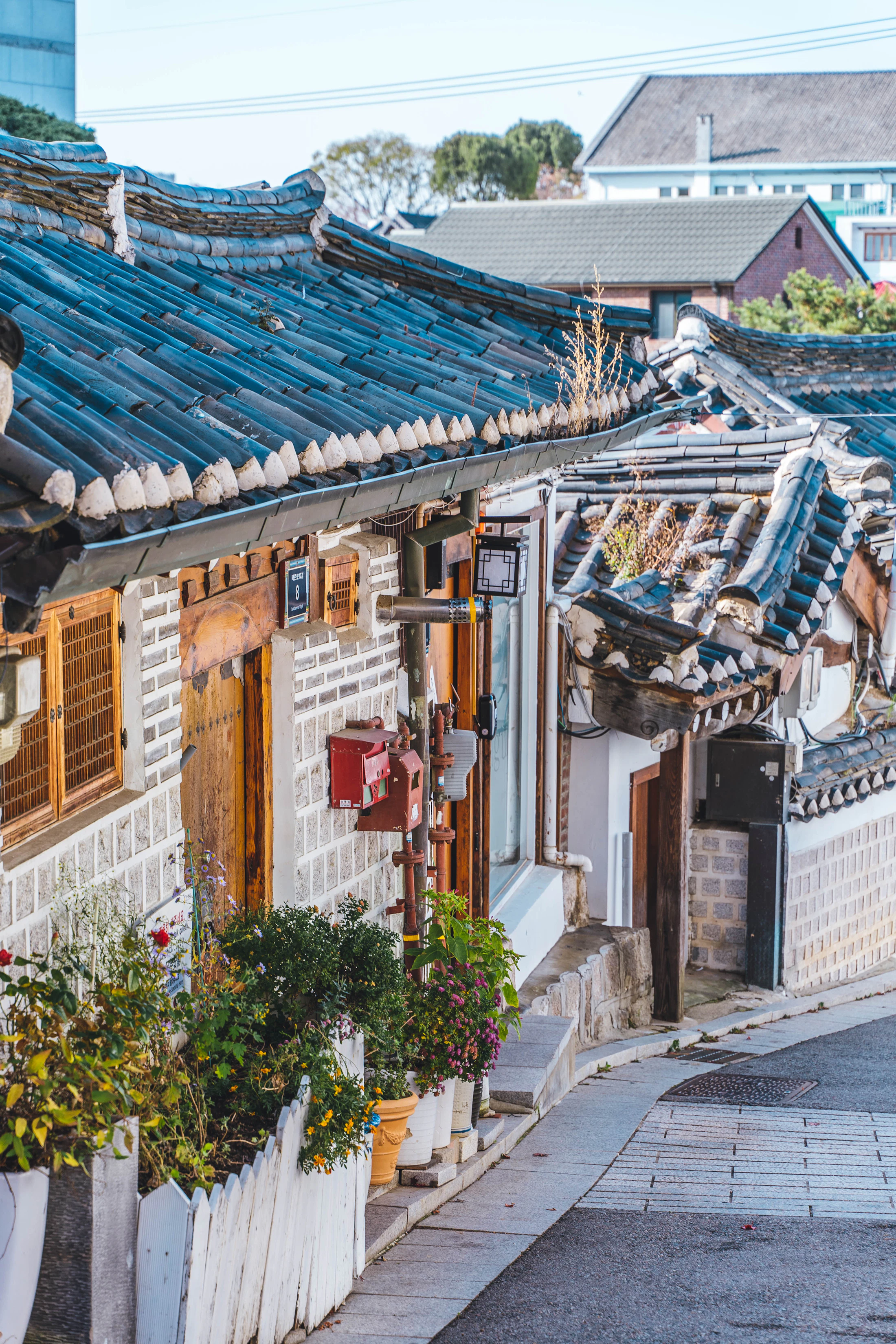 A quiet alley in Bukchon at dusk, lined with tiled hanok rooftops