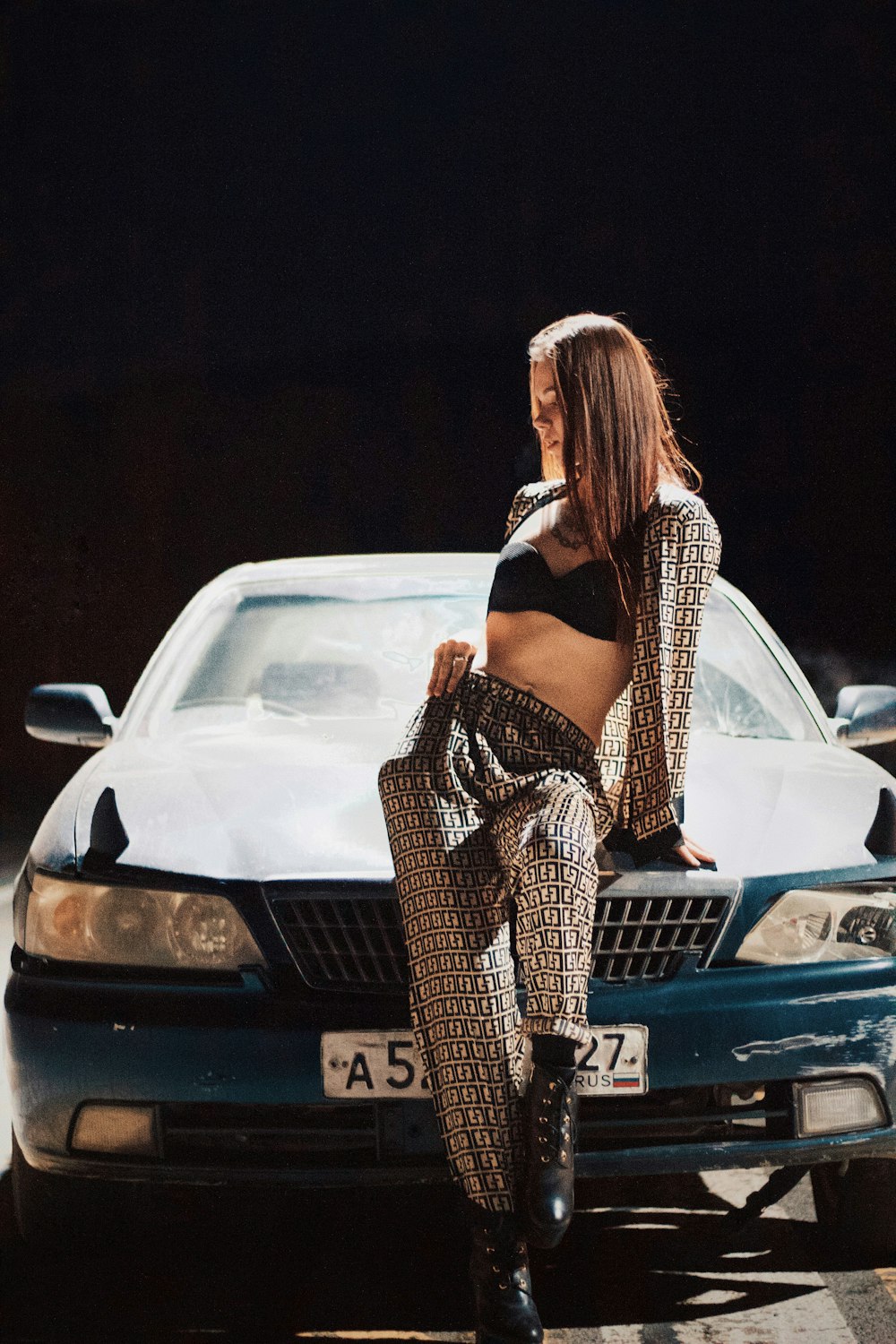 a woman sitting on the hood of a car