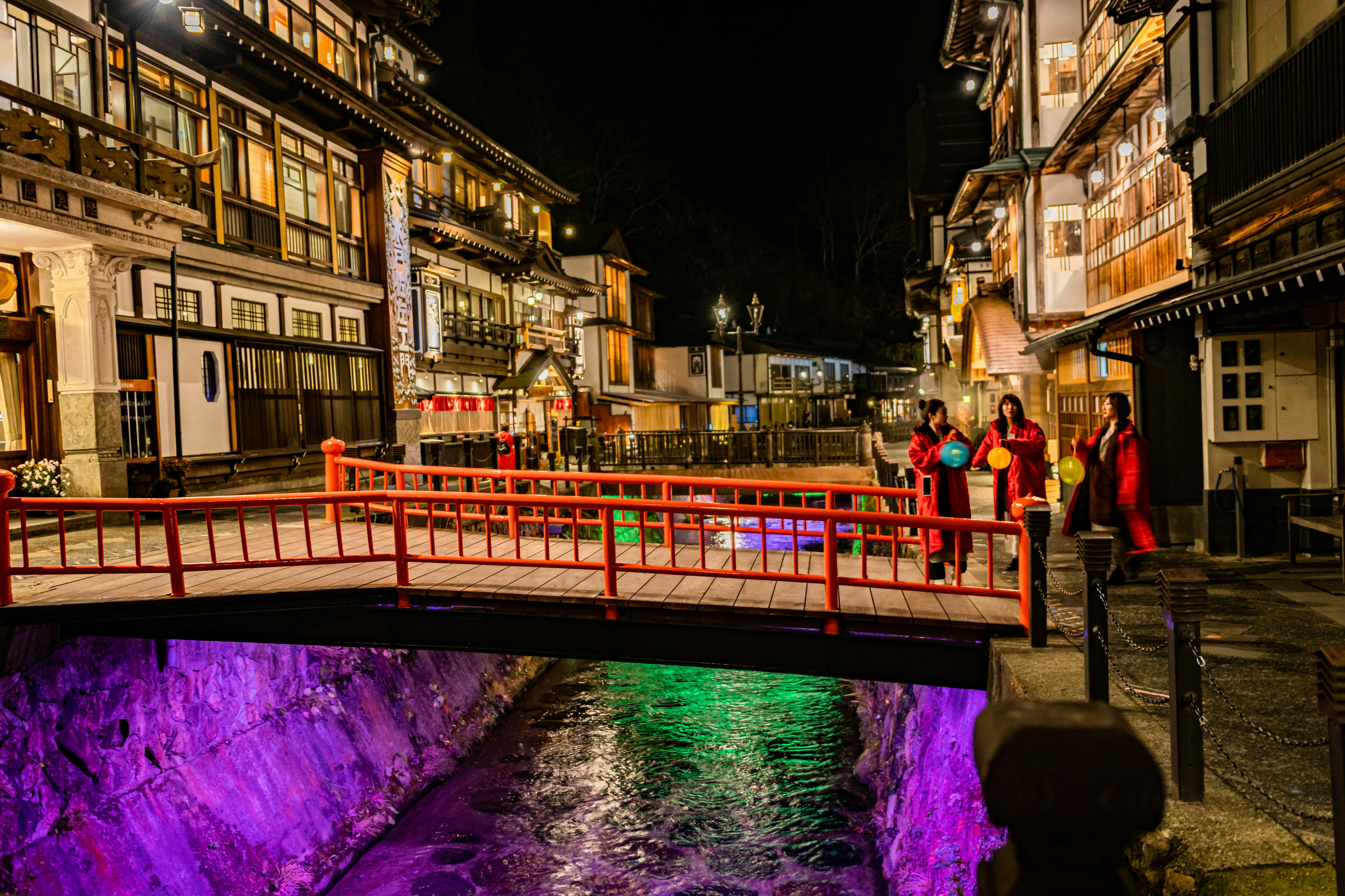 밤에 도시의 강 위의 빨간 다리