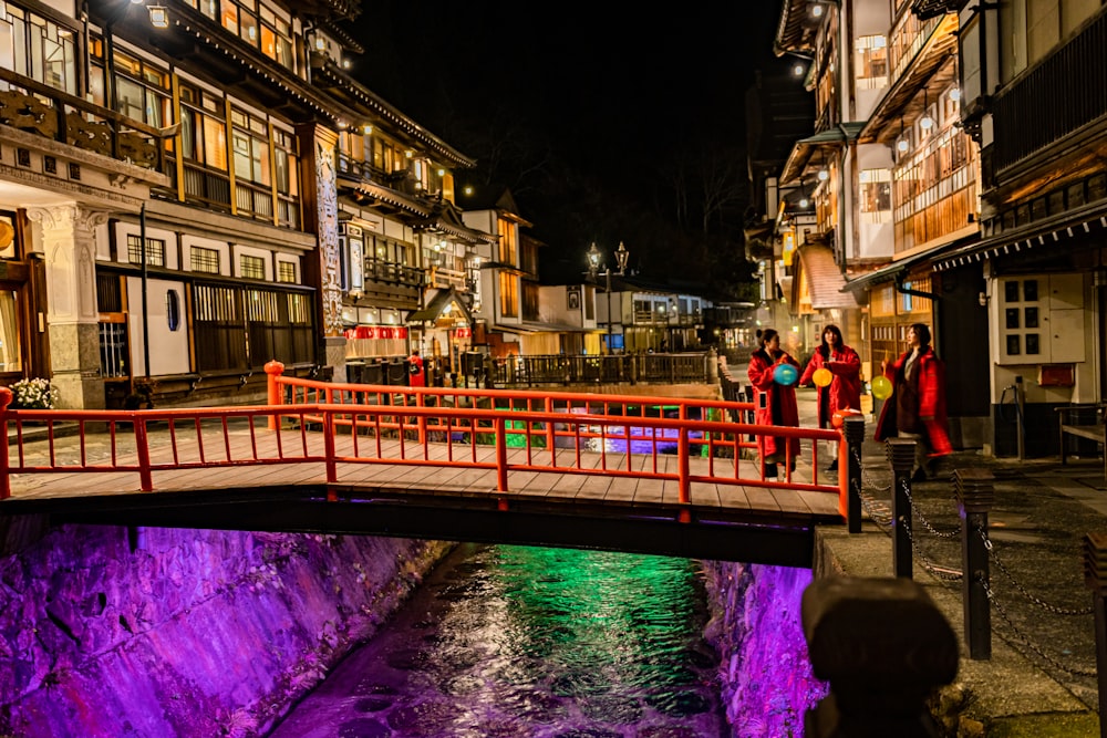 a red bridge over a river in a city at night