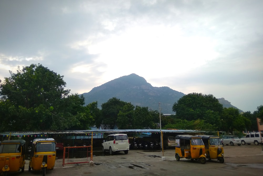 a parking lot with several buses parked in front of a mountain