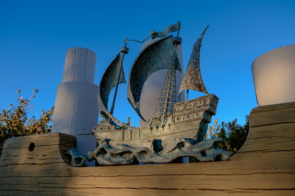 a statue of a boat with sails on top of a wooden structure