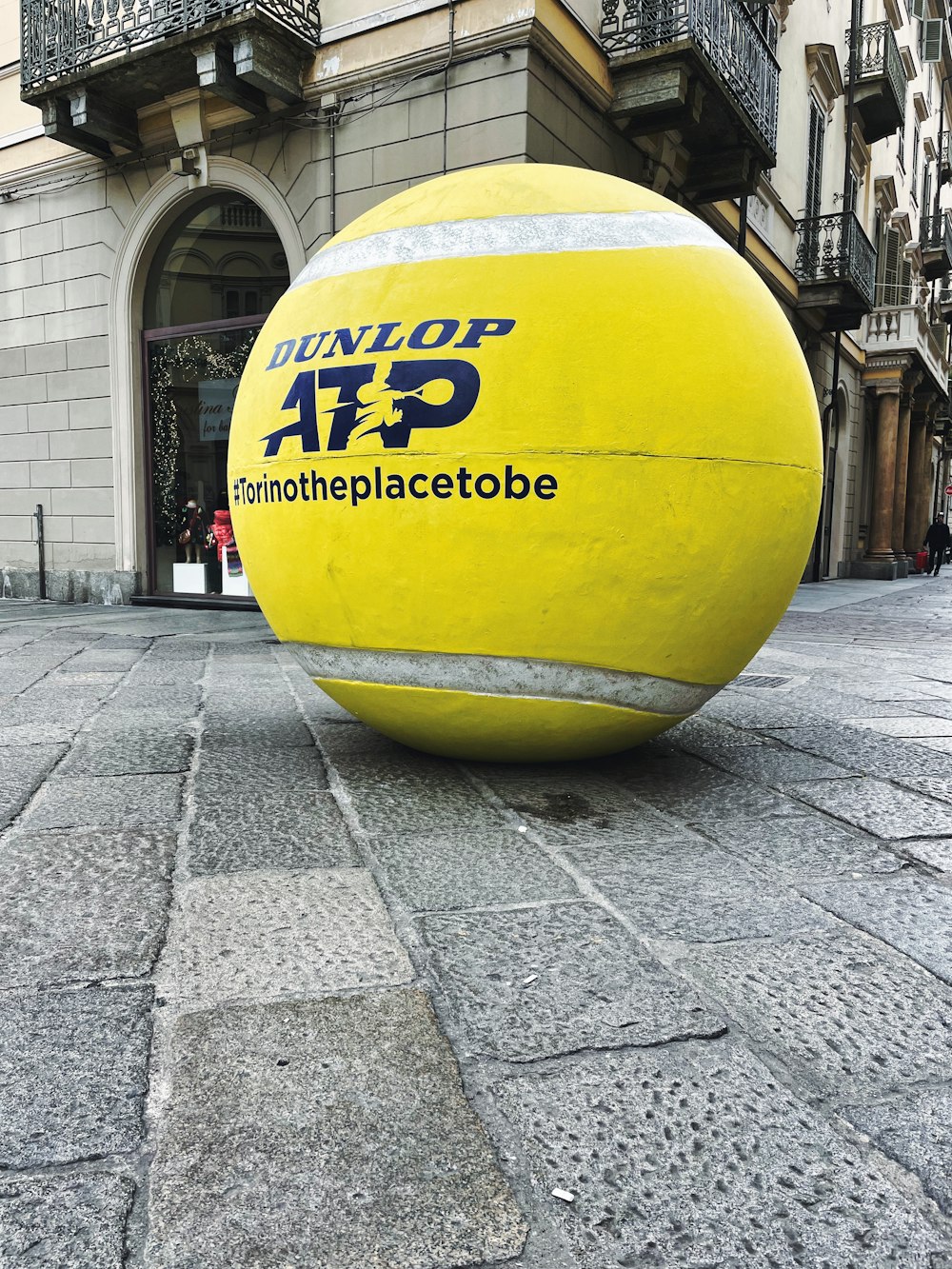 a large yellow ball sitting on top of a sidewalk