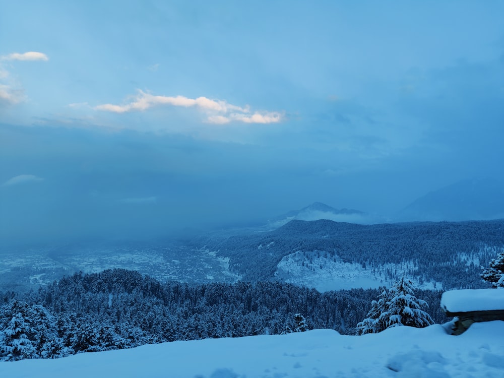 a view of a snowy mountain with a bench in the foreground