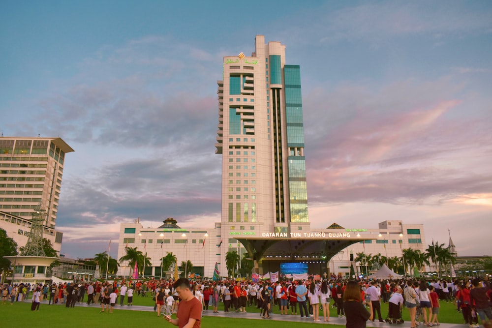 a crowd of people standing in front of a tall building