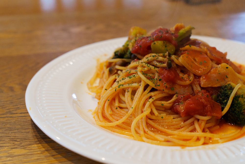 a plate of spaghetti with broccoli and tomatoes