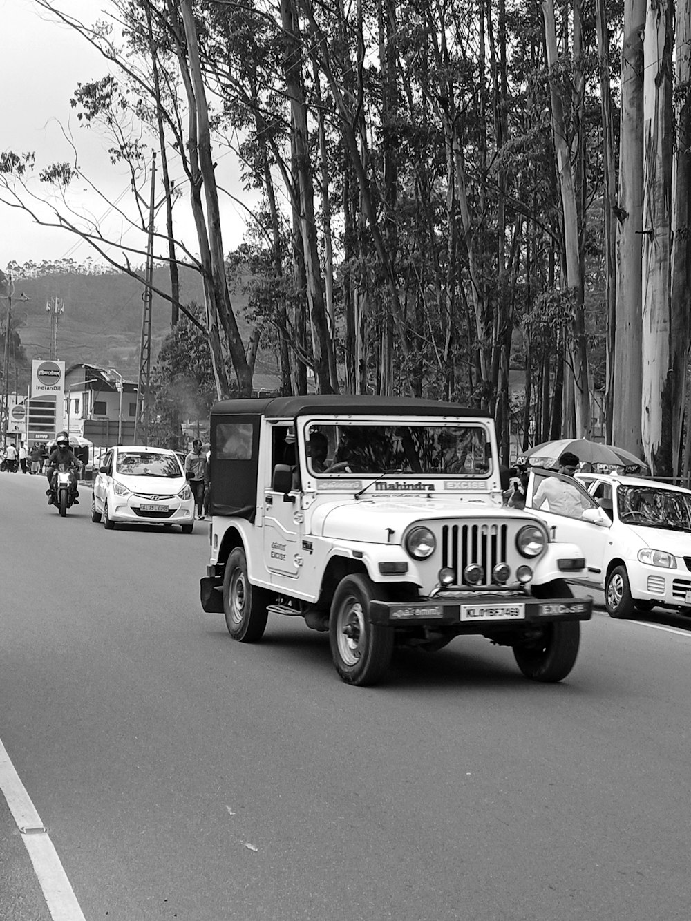 a black and white photo of a jeep driving down a street