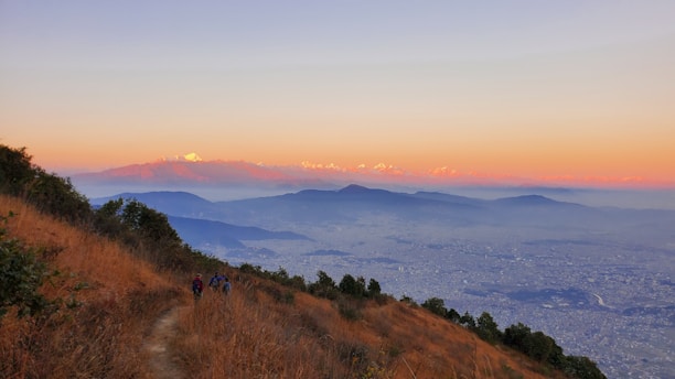 A scenic mountain landscape with travelers enjoying a sunrise hike.