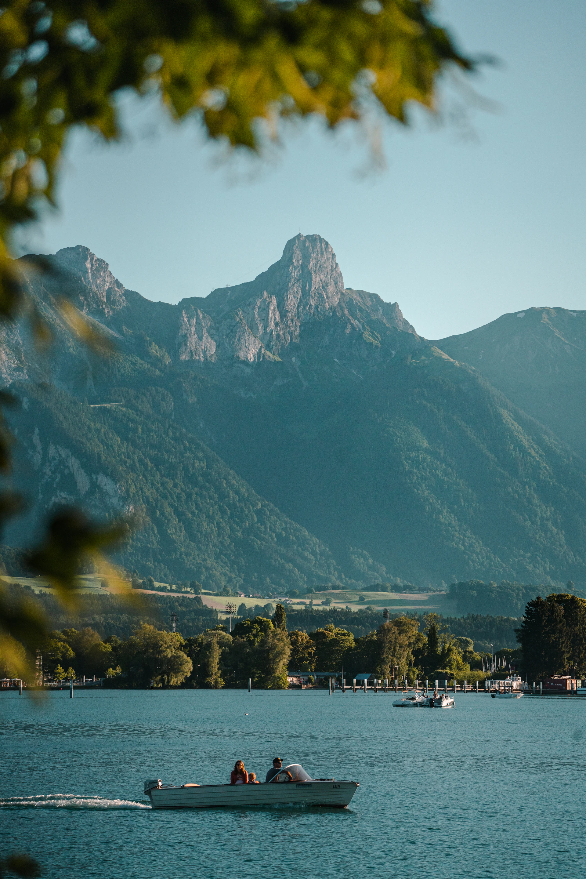 An engaging image of a group enjoying a scenic boat ride on a serene Guatemalan lake, framed by volcanoes under a clear blue sky.