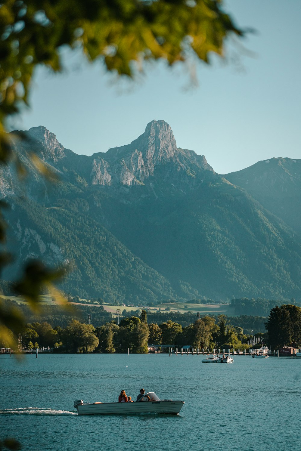 duas pessoas em um barco em um lago com montanhas ao fundo