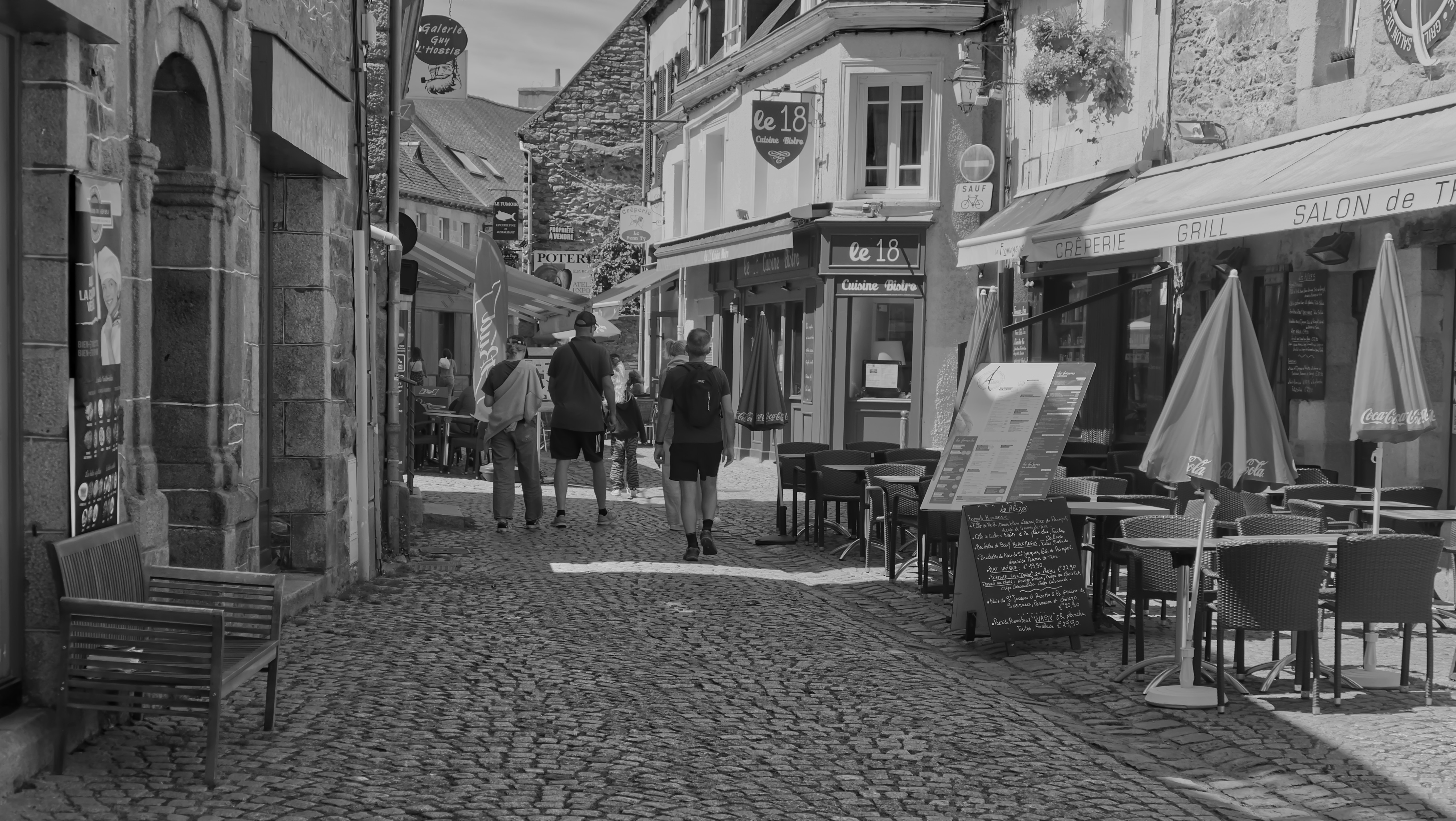 a black and white photo of people walking down a cobblestone street