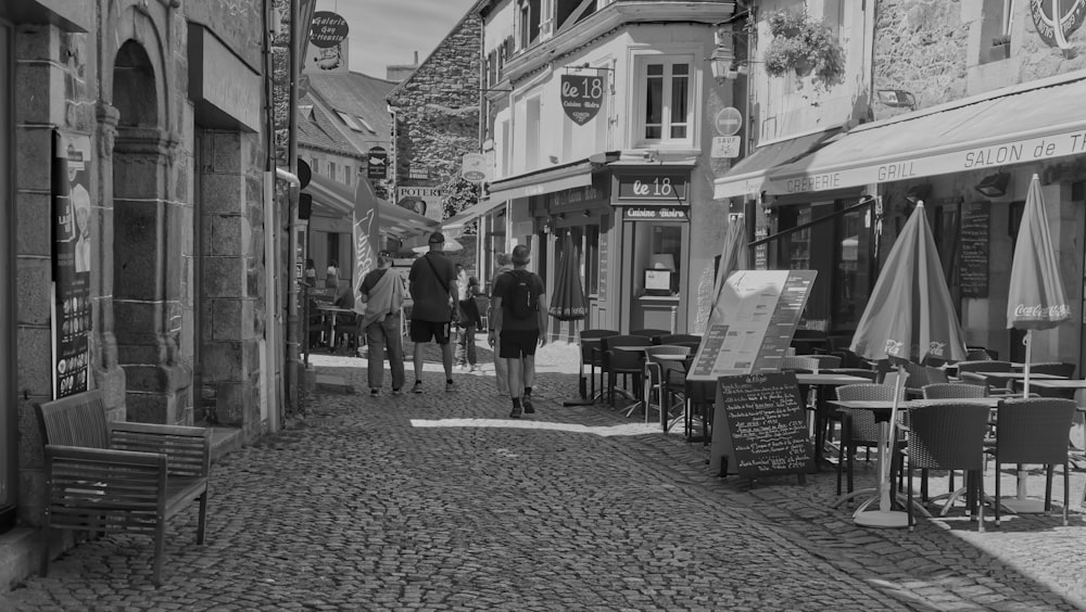 a black and white photo of people walking down a cobblestone street