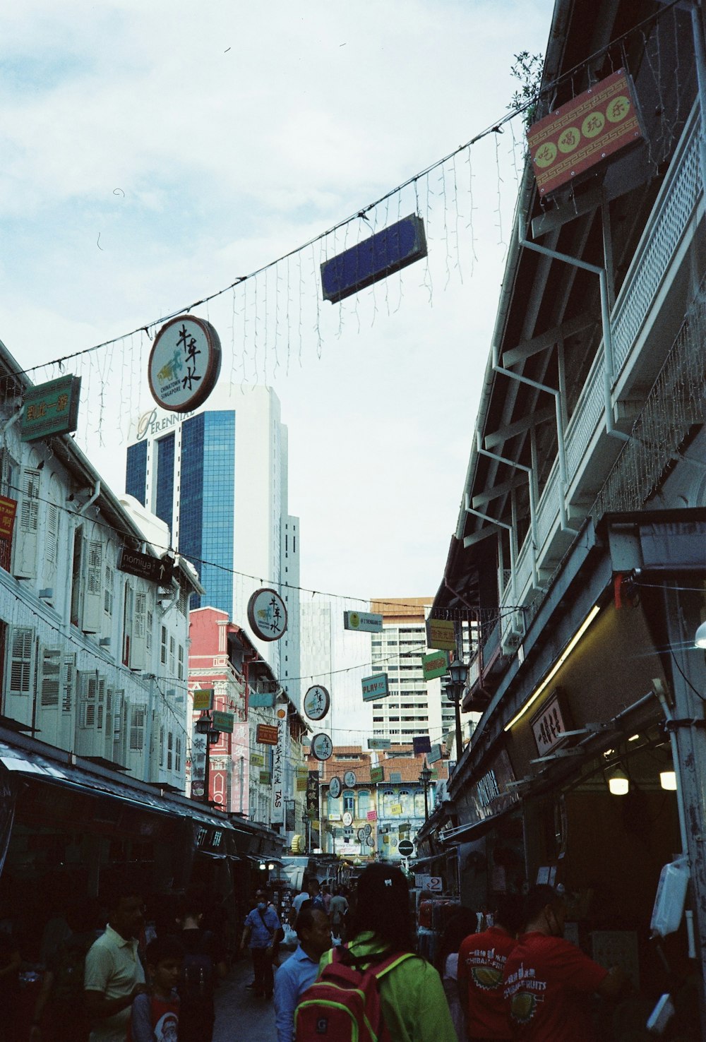 a group of people walking down a street next to tall buildings