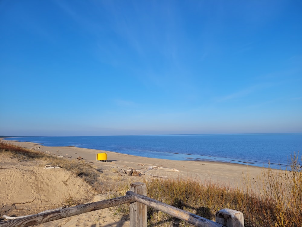 a beach with a wooden fence and a body of water