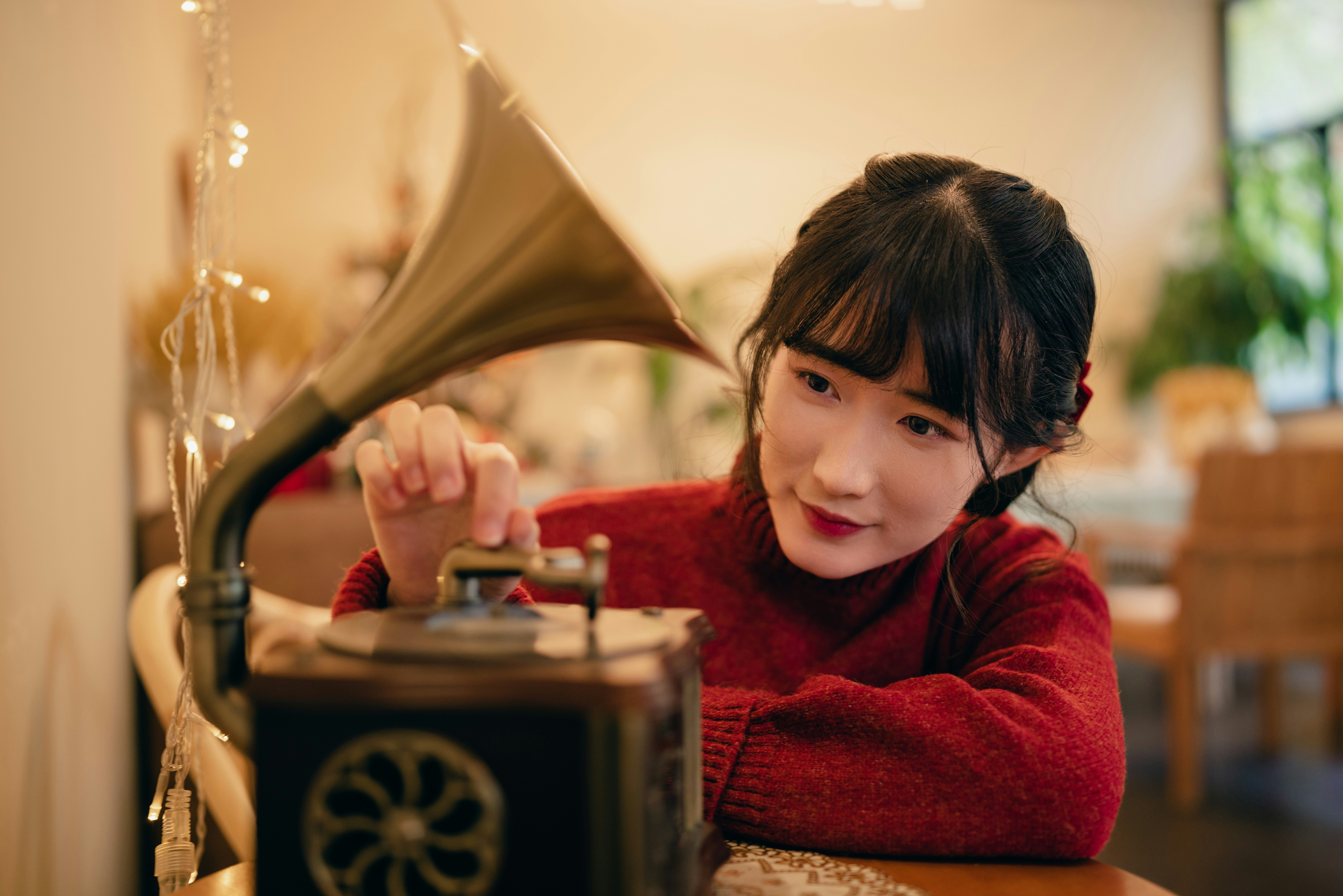 a young girl sitting at a table with a record player, 