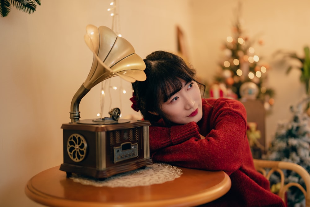 a woman sitting at a table next to a christmas tree