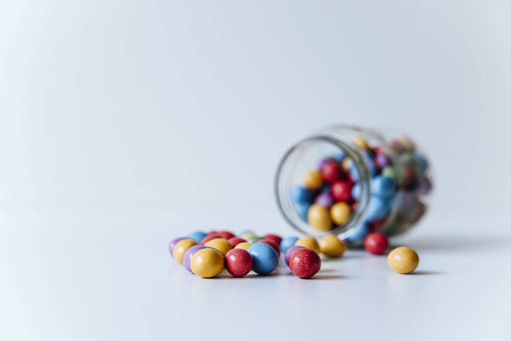 a glass jar filled with colorful candies on top of a table