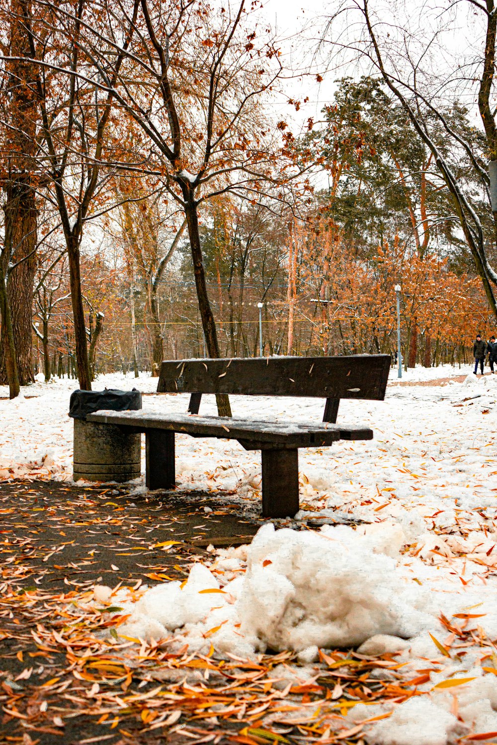 a park bench covered in snow next to trees
