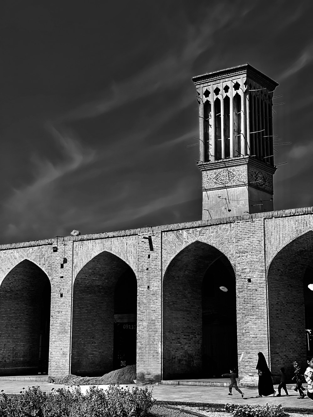 a black and white photo of a building with arches and a clock tower