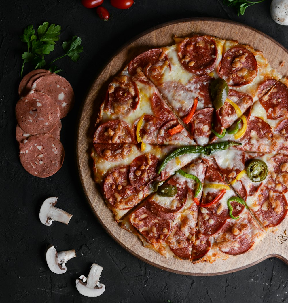 a pizza with pepperoni, peppers, and mushrooms on a cutting board