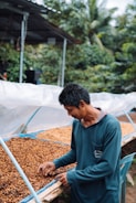 a man standing in front of a pile of coffee beans