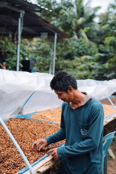 a man standing in front of a pile of coffee beans