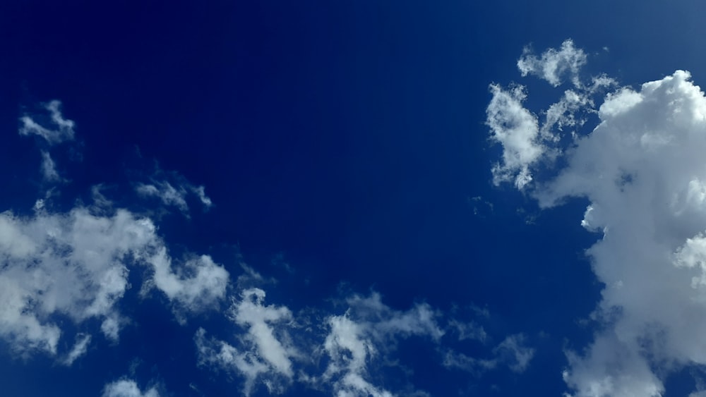 a plane flying through a blue sky with clouds